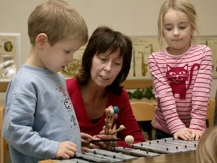 Lehrerin mit Junge und Mädchen am Xylophon