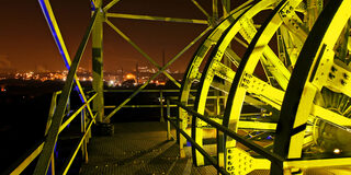 Detailaufnahme Förderturm (Räder) nachts gelb beleuchtet