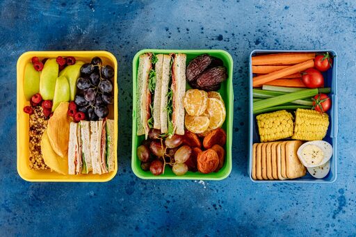Brotdosen gefüllt mit Sandwiches, Obst, Gemüse