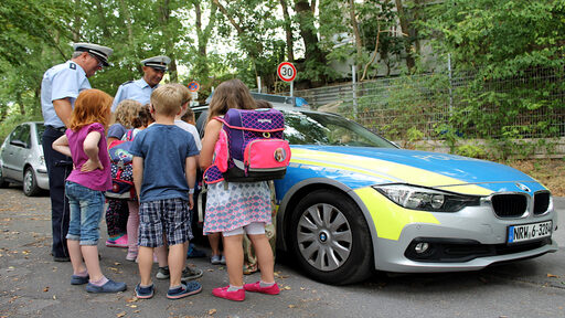 Polizisten im Gespräch mit Schulkindern vor einem Einsatzfahrzeug