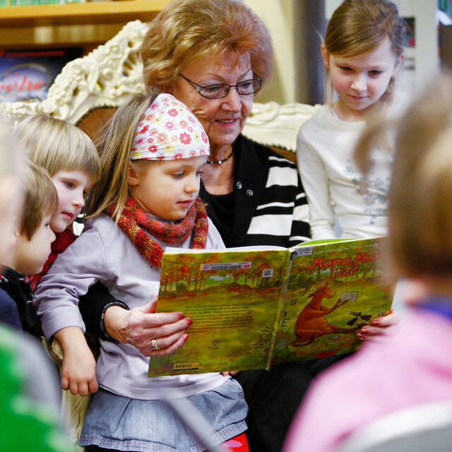 Frau liest Kindern vor.