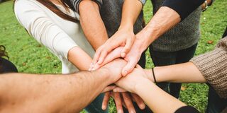 Leute halten ihre Hände zusammen und übereinander