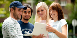 Vier Studenten schauen auf einen Laptop