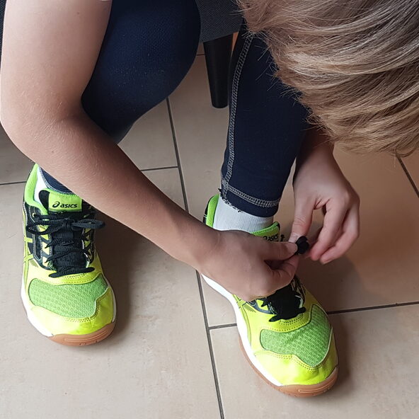 Kind bindet sich eine Schleife