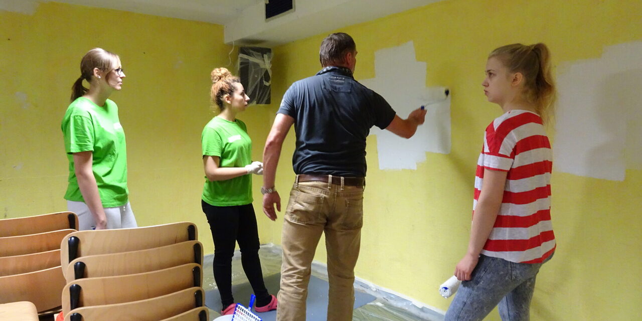 Vier Personen streichen eine Wand