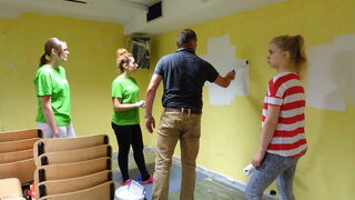 Vier Personen streichen eine Wand