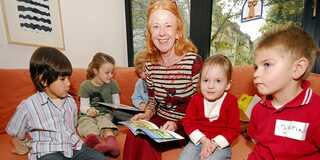 Frau liest Kindern aus einem Buch vor