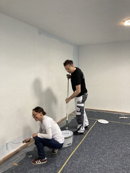 Zwei Mitarbeitende von Aurelis streichen die Wand.