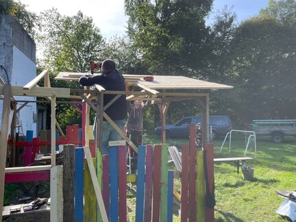 Mitarbeitende reparieren das Dach des Holzhauses.