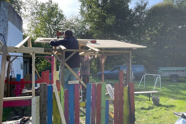 Mitarbeitende reparieren das Dach des Holzhauses.