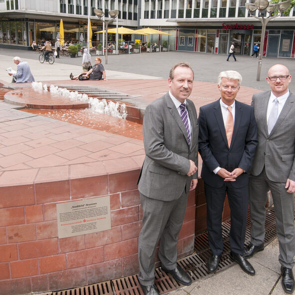 Paten vor dem Brunnen und der Sparkasse