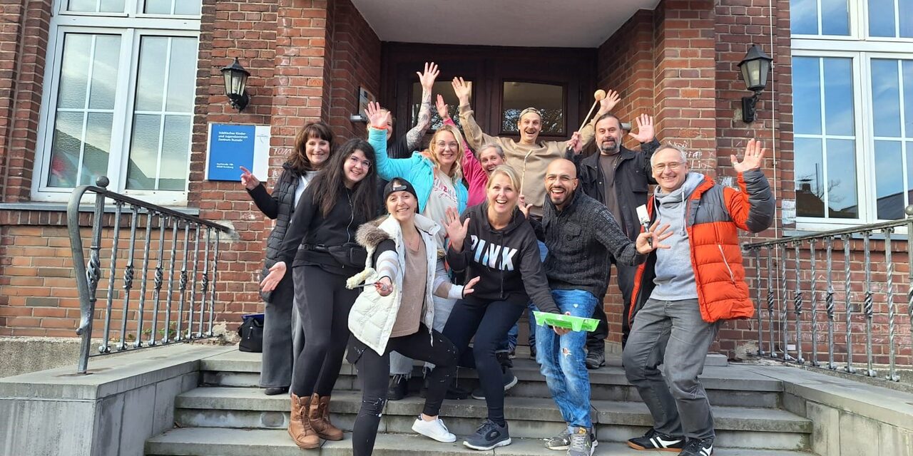 Gruppenfoto der Mitarbeiterinnen und Mitarbeiter der Targobank auf den Stufen des Kinder- und Jugendzentrums in Rumeln
