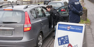 Eine Mitarbeiterin der Stadt Duisburg und ein Polizeibeamter geben vor der Schule Tipps zum richtigen Verhalten.