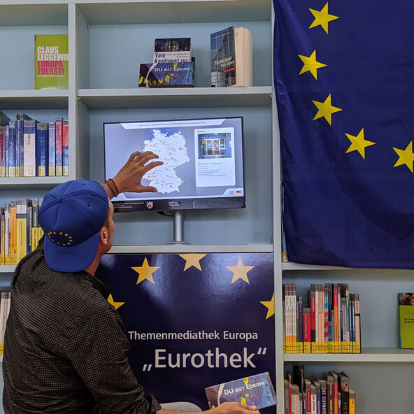 Jugendlicher vor Regal mit Europa-Büchern
