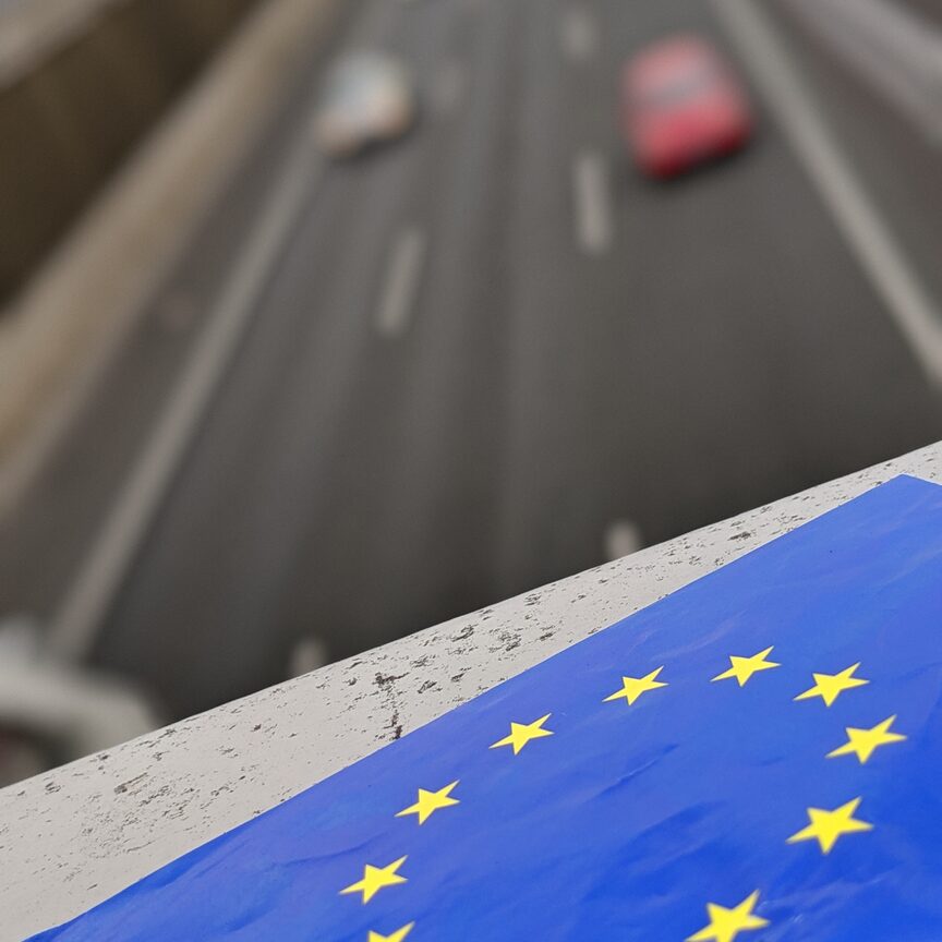 EU-Fahne auf Brücke mit Autos im Hintergrund