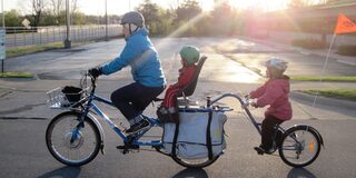 Elternteil und 2 Kinder auf einem Fahrrad