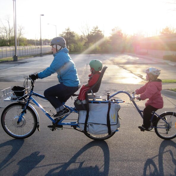 Elternteil und 2 Kinder auf einem Fahrrad