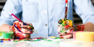 Eine Person malt mit farbverschmierten Händen