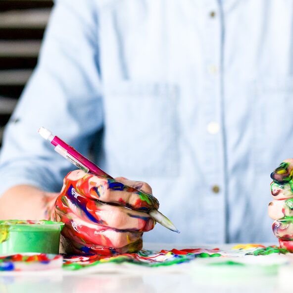Eine Person malt mit farbverschmierten Händen