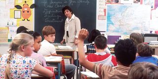 Eine Schulklasse, die gerade Englisch lernt; ein Schüler meldet sich