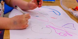 Das Bild zeigt die Hände eines Kindes, die gerade ein Bild malen.