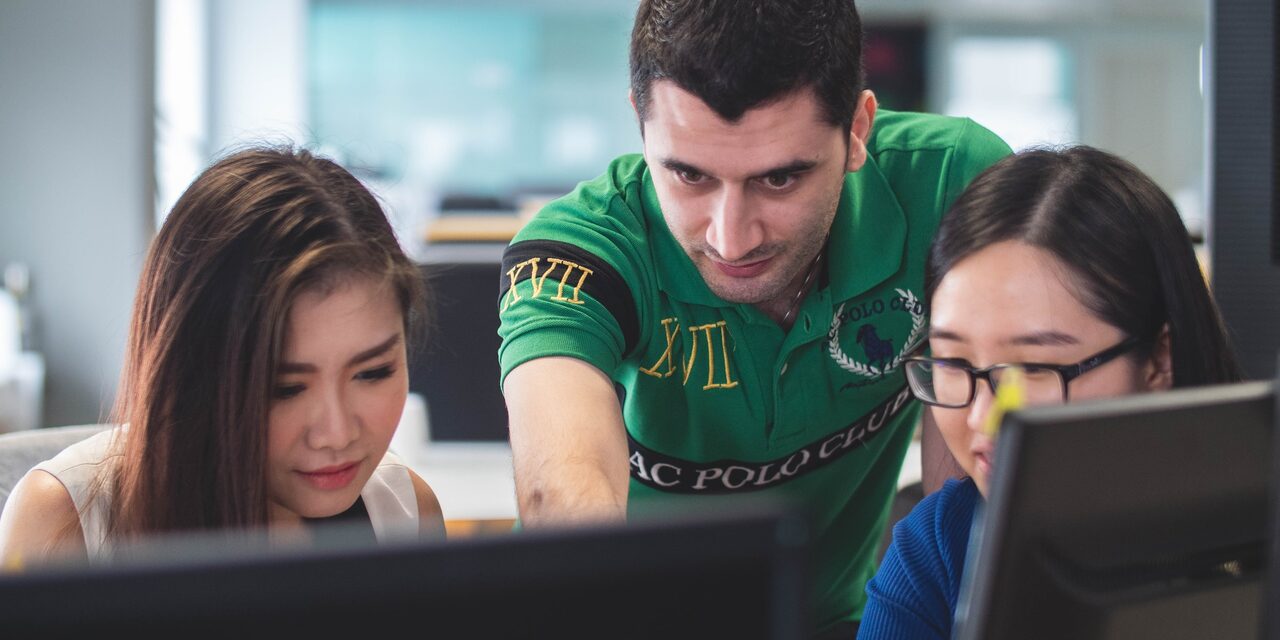 Ein Praktikant guckt seinen Kolleginnen über die Schulter