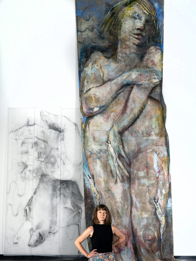 Die Künstlerin Lisa Wölfel steht vor einem ihrer großen Gemälde