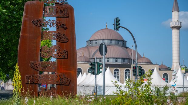 Die Dialogskulptur von Yildirim Denizli, im Hintergrund ist die Moschee zu sehen