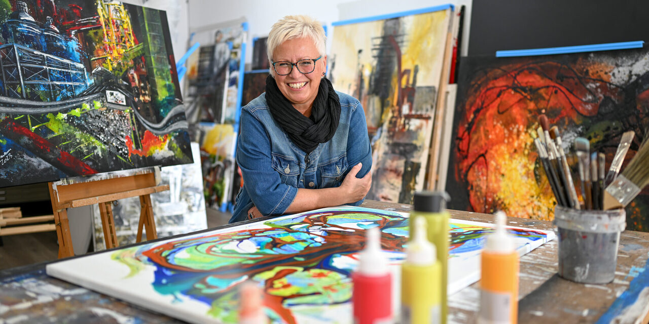Frau in ihrem Atelier mit Bildern und Farben