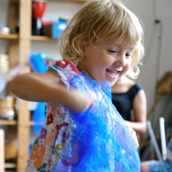 Mädchen spielt mit blauem Stoff