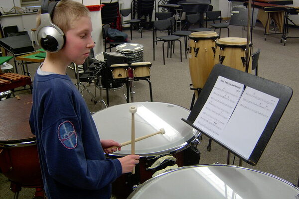 Kleiner Junge mit Kopfhörern am Schlagzeug