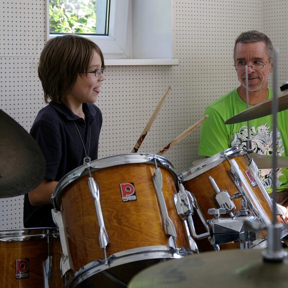 Junge am Schlagzeug, Lehrer sitzt daneben