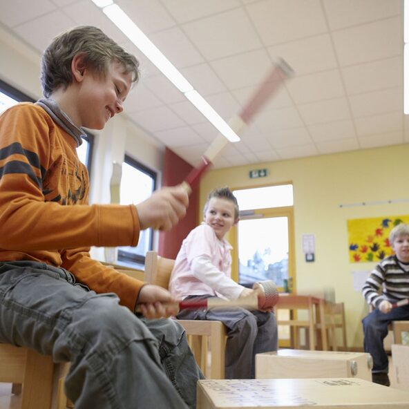 Drei Kinder mit Instrumenten in einem Klassenraum
