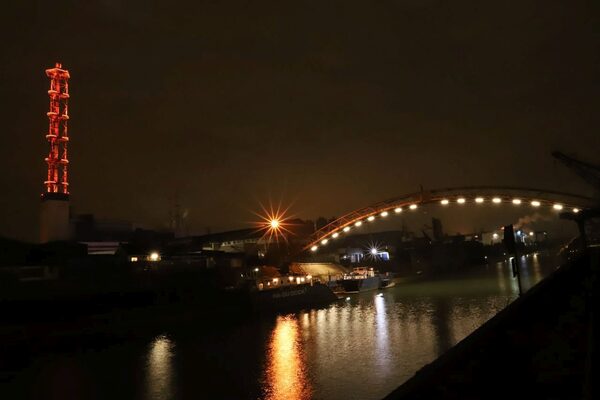 Links der Stadtwerketurm in orange, rechts die beleuchtete Brücke über den Hafen