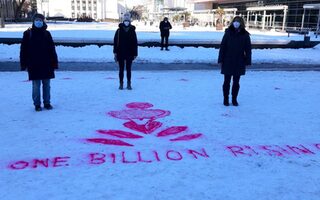 Die 3 Mitarbeiterinnen stehen mit Maske hinter dem in den Schnee gesprühten LOGO von One Billion Rising