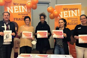 5 Personen halten Aktionsschilder des Hilfetelefons mit der Aufschrift "Wir brechen das Schweigen" in der Hand