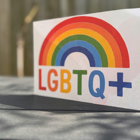 Schild mit LGBTQ+ und einem Regenbogen