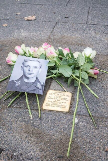 Der Stolperstein ist mit Rosen und einem Foto von Wilhelm Kühlen geschmückt