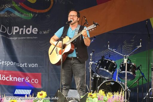 Singende Person mit Gitarre auf der Bühne