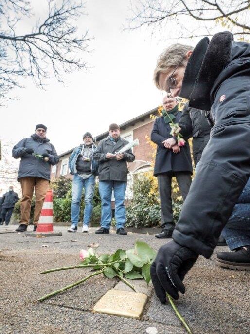 Eine Frau legt Rosen neben den Stolperstein