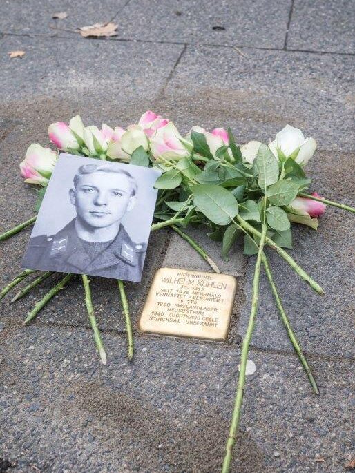 Der Stolperstein ist mit Rosen und einem Foto von Wilhelm Kühlen geschmückt