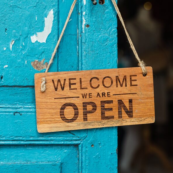 Blaue Tür mit Holzschild "Welcome we are open"