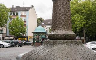 Steinskulpturenbrunnen auf dem Hamborner Altmarkt. Im Hintergrund ist die historische Trinkhalle (heute Imbiss) zu sehen.