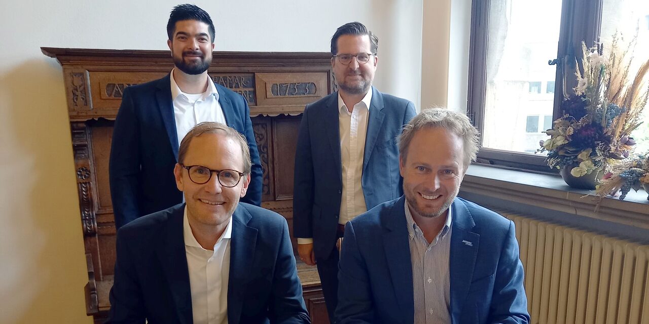 v. l. (vorne) Stefan Rüter, Chief Commercial Officer OXG, und Stadtdirektor und Digitalisierungsdezernent Martin Murrack bei der Unterzeichnung des Letter of Intent; (stehend) Thomas Preiß, Key Account Manager Kommunen und Timo Seidel, General Counsel OXG