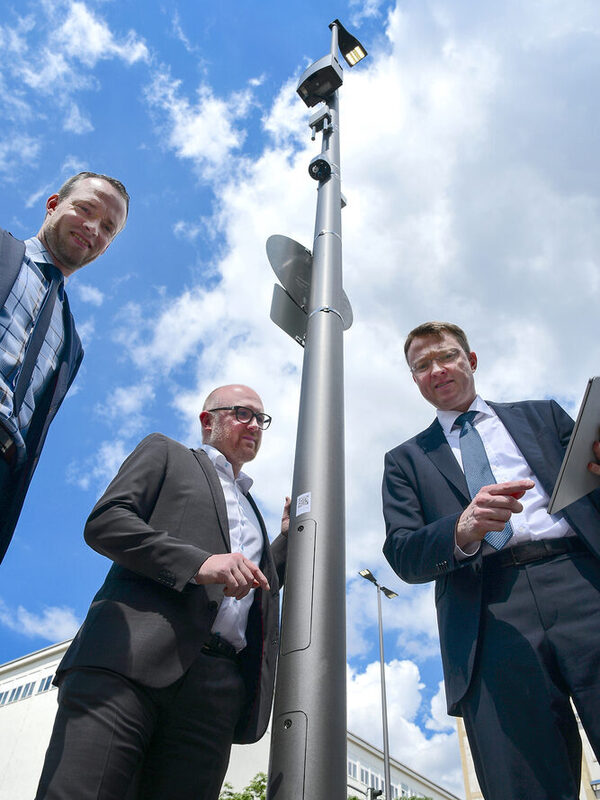 Andreas Gutschek (Vorstand Infrastruktur und Digitalisierung der Stadtwerke Duisburg AG), Oberbürgermeister Sören Link und Marcus Vunic (Geschäftsführer Recht, Informationstechnologie, Telekommunikation und Digitalisierung der DVV, v.l.) an einer der smarten Straßenlaternen, ausgestattet mit WLAN-Hotspot, Geräuschsensor und energiesparender LED-Technik