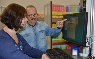 Mann berät Frau am PC