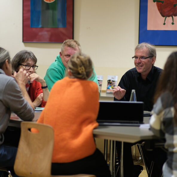 Menschen sitzen um einen Tisch und Diskutieren