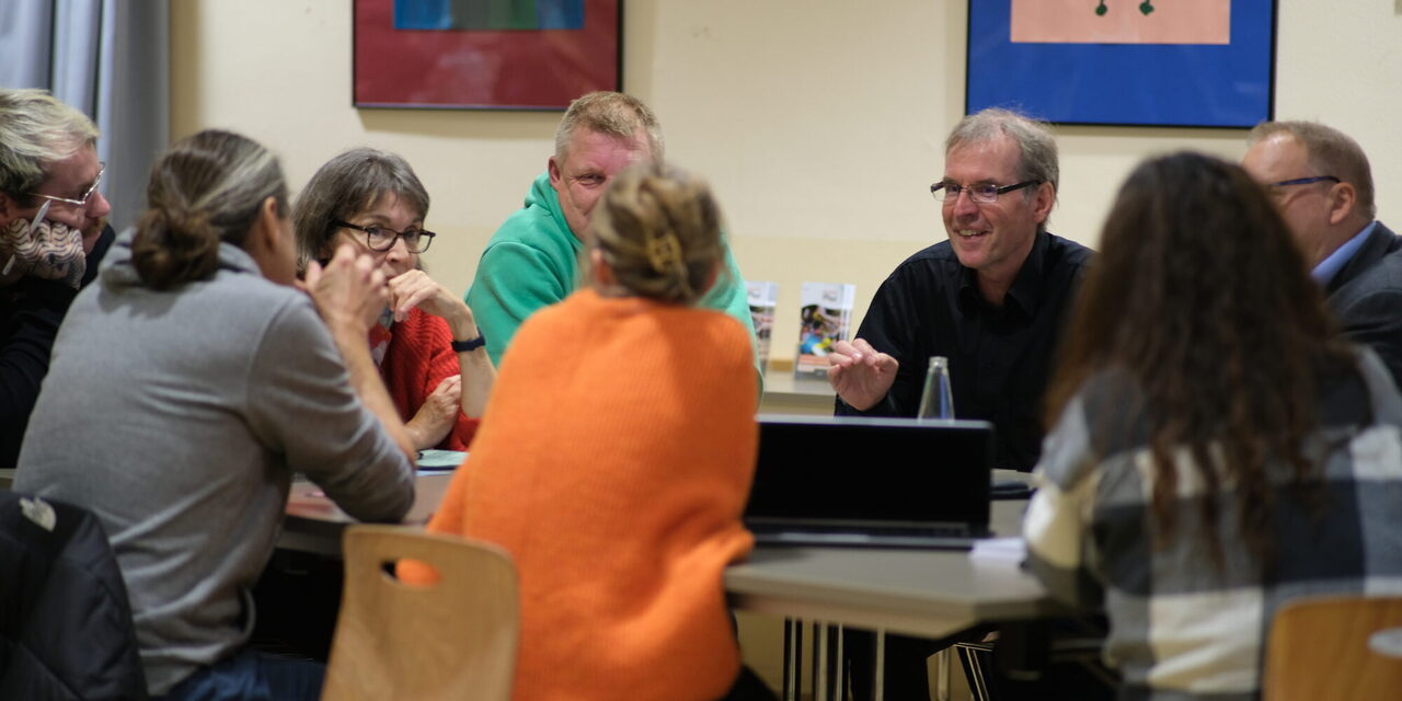 Menschen sitzen um einen Tisch und Diskutieren