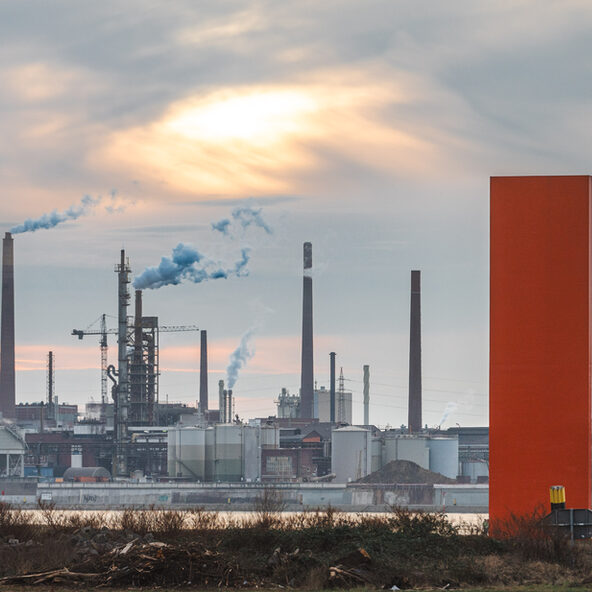 Industriekulisse hinter der Skulptur Rhein-Orange in Duisburg