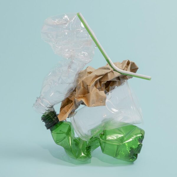 Zerdrückte Plastikflaschen und Müll auf einem hellblauen Hintergrund